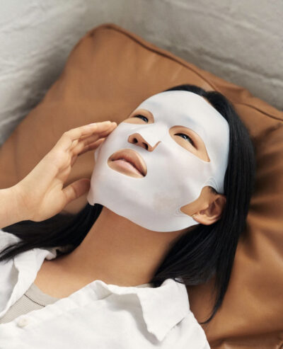 A model lying down and wearing a sheet mask